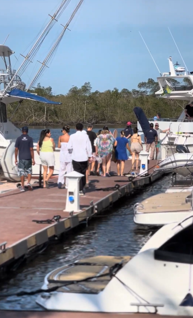 Visitantes caminhando entre as embarcações no píer da marina